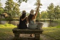 two friend girls with hats chatting sitting on a stone bench in front of the river Royalty Free Stock Photo