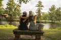 two friend girls with hats chatting sitting on a stone bench in front of the river Royalty Free Stock Photo