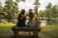 two friend girls with hats chatting sitting on a stone bench in front of the river Royalty Free Stock Photo