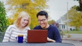 Two friend multiethnicity - Korean man and a Caucasian woman working together or watching a video on a laptop.