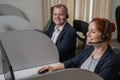 Two friendly call center employees answer customers by phone. Man and woman woman talking on a headset in the office. Royalty Free Stock Photo