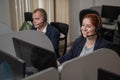 Two friendly call center employees answer customers by phone. Man and woman woman talking on a headset in the office. Royalty Free Stock Photo