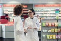 Two friendly colleagues talking while working together in a modern drugstore