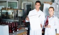 Two friendly employees standing in packaging section on wine manufactory