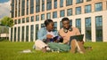 Two friends African American ethnic students sitting on green grass meadow lawn in park outdoors woman man girl guy Royalty Free Stock Photo