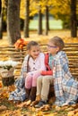 Two friends: a boy and a girl in autumn park sitting on wooden bench near a fence Royalty Free Stock Photo