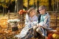 Two friends: a boy and a girl in autumn park sitting on wooden bench near a fence Royalty Free Stock Photo