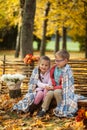 Two friends: a boy and a girl in autumn park sitting on wooden bench near a fence Royalty Free Stock Photo