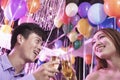 Two friends celebrating, toasting with champagne, nightclub in Beijing, balloons in the background Royalty Free Stock Photo