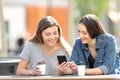 Two friends checking smart phone online content in a park Royalty Free Stock Photo