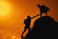Two friends climbing on mountain peak on sunset