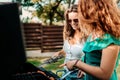 Two female friends cooking on barbeque grill, having lunch in nature with friends Royalty Free Stock Photo