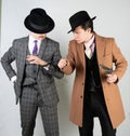 Two friends dressed in vintage clothes and depict retro detectives and spies in English classic style on a white studio background