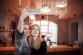 Two friends drinking coffee in a cafe, taking selfies with a smart phone and having fun making funny faces. Focus on the Royalty Free Stock Photo