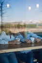 Two friends are enjoying coffee in a coffee shop, looking through a glass with reflections, sitting at a table chatting Royalty Free Stock Photo