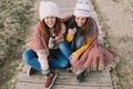 Two friends have a fit of laughter while drinking broth sitting in the middle of the meadow