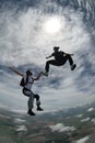 Two friends having fun in freefall. Against the sun