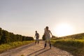 Two friends are having fun inline skating down a dirt path surrounded by greenery under a clear blue sky during late afternoon Royalty Free Stock Photo