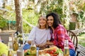 Two friends are having fun at a picnic table. A blonde european and afroamerican girls are hugging on a picnic in the Royalty Free Stock Photo