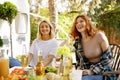 Two friends are having fun at a picnic table. A blonde and a redhaired girl are hugging on a picnic in the forest Royalty Free Stock Photo