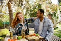 Two friends are having fun on a picnic, telling jokes, drinking drinks. A redhaired girl and an African American oy are Royalty Free Stock Photo