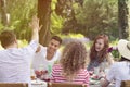 Two friends high-fiving each other and their girlfriends laughing during a garden party in the summer