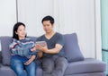 Two friends on line with multiple devices and talking sitting on a sofa in the living room in a house interior Royalty Free Stock Photo