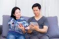 Two friends on line with multiple devices and talking sitting on a sofa. Royalty Free Stock Photo