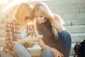 Two beautiful students watching media content on line in smart phone in park Royalty Free Stock Photo