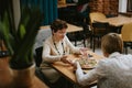 Two friends meet and have dinner at restaurant, aged dressy ladies with eat tasty pizza at table in cafe hall. Old