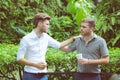 Two friends men talking standing in a garden. Royalty Free Stock Photo