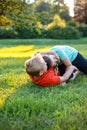 Two friends play rolling on the grass, spending time together happily. Relaxing kids outdoor.