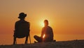 Two friends rest on the shore of the lake at sunset, fishing. Friendship and relaxation in the open air Royalty Free Stock Photo