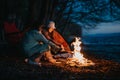 Friends enjoying a warm bonfire by the lakeside during a camping trip Royalty Free Stock Photo