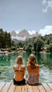 Two friends savoring a serene moment by an alpine lake, gazing at the majestic mountains