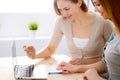 Two friends or sisters talking taking a conversation at the table with laptop