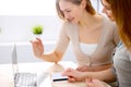 Two friends or sisters talking taking a conversation at the table with laptop