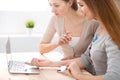 Two friends or sisters talking taking a conversation at the table with laptop