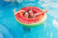 Two friends with sunglasses in watermelon ring lilo. Young women enjoy the summer at swimming pool. Hand victory sign gesture. Fun Royalty Free Stock Photo