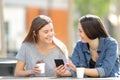 Two friends talking about phone content in a park Royalty Free Stock Photo