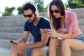 Two friends using mobile phone and listening to music in the str Royalty Free Stock Photo