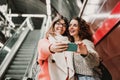 Two friends waiting going down stairs at the station before catching a train. Taking selfie with mobile phone. Travel photography Royalty Free Stock Photo