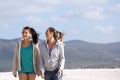 Two friends walking on the beach smiling Royalty Free Stock Photo