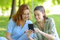 Two friends watching phone content in a park Royalty Free Stock Photo