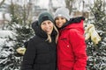 Two friends in winter coats sitting fire in forest