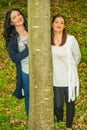 Two friends women behind tree