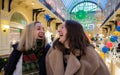 Two friends young women laughing on background of brightly decorated for Christmas shopping mall Royalty Free Stock Photo