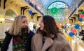 Two friends young women smiling on background of brightly decorated for Christmas shopping mall Royalty Free Stock Photo