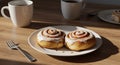 Two Frosted Cinnamon Rolls with Coffee Cups on a Wooden Table Royalty Free Stock Photo