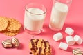 Two full glasses of fresh milk, yogurt or kefir near thin waffles, chocolate candies, marshmallow on pink